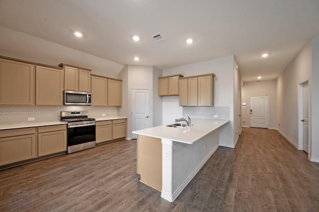 kitchen with sink, hardwood / wood-style flooring, a breakfast bar, backsplash, and stainless steel appliances