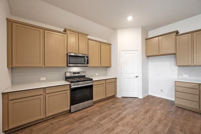 kitchen with tasteful backsplash, wood-type flooring, and stainless steel appliances