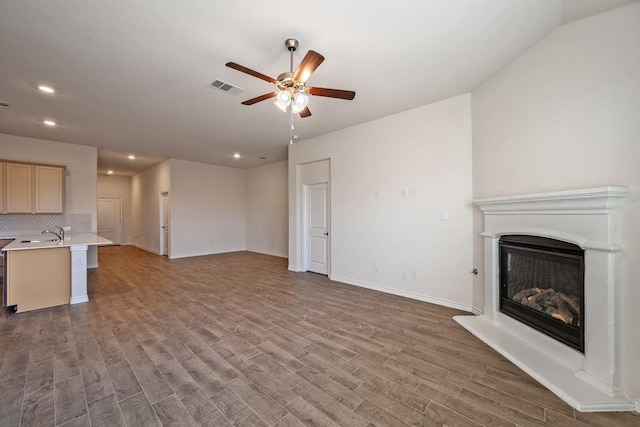 unfurnished living room with ceiling fan, dark hardwood / wood-style flooring, and sink