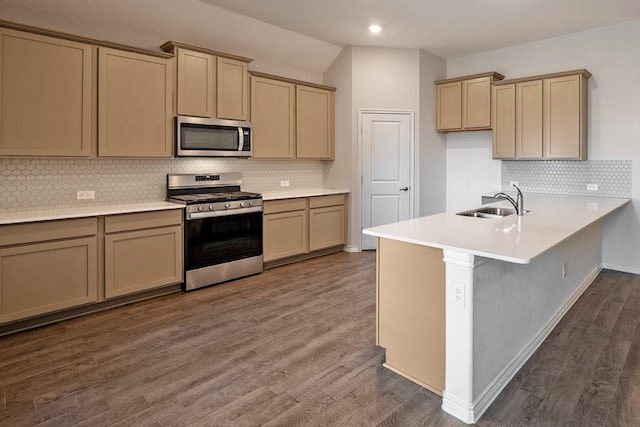 kitchen featuring stainless steel appliances, dark hardwood / wood-style floors, kitchen peninsula, and sink