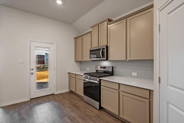 kitchen with stainless steel appliances, vaulted ceiling, dark wood-type flooring, and backsplash