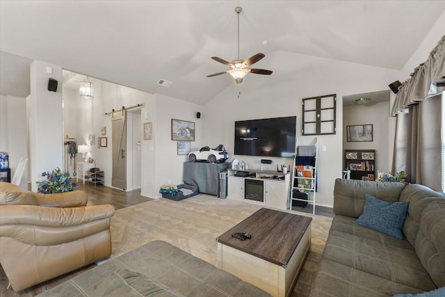 living room featuring ceiling fan, a barn door, and vaulted ceiling