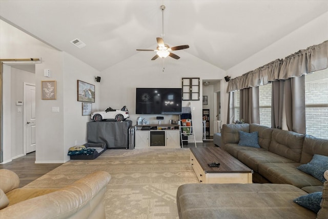 living room featuring lofted ceiling, ceiling fan, wood finished floors, visible vents, and baseboards