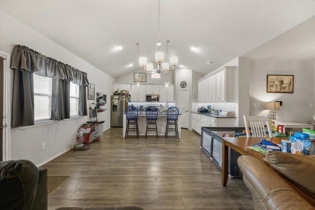 kitchen featuring dark hardwood / wood-style floors, white cabinets, hanging light fixtures, a kitchen island with sink, and stainless steel appliances