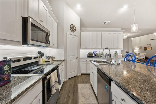 kitchen with vaulted ceiling, stone countertops, pendant lighting, sink, and white cabinets