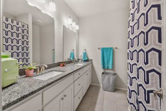 full bathroom with baseboards, double vanity, a sink, and tile patterned floors