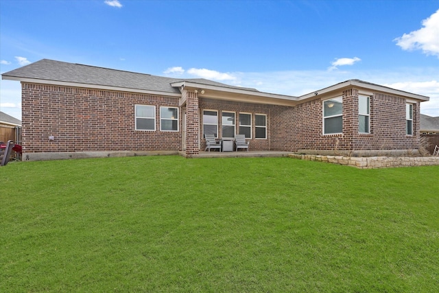 rear view of property with brick siding, a lawn, and roof with shingles