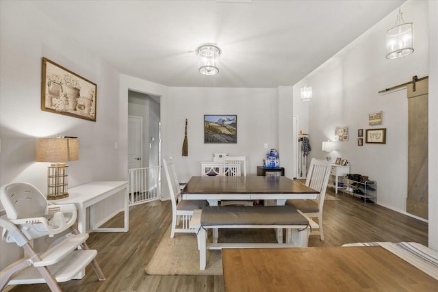 dining room featuring a barn door and dark hardwood / wood-style flooring