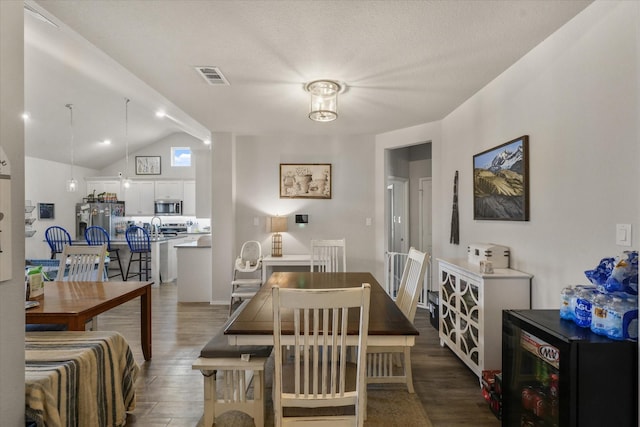 dining room featuring beverage cooler, visible vents, lofted ceiling with beams, and wood finished floors