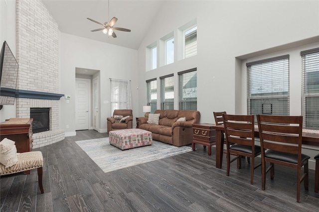 living room with a fireplace, dark wood-type flooring, high vaulted ceiling, and ceiling fan