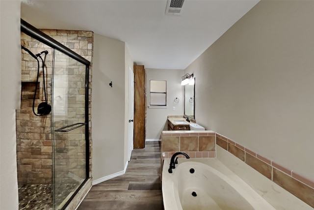 bathroom with vanity, hardwood / wood-style floors, and plus walk in shower