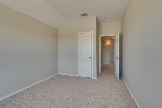 unfurnished bedroom with vaulted ceiling and light carpet