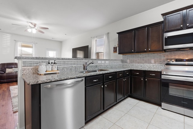 kitchen with dark brown cabinetry, sink, kitchen peninsula, and appliances with stainless steel finishes