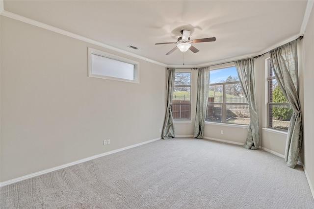 carpeted spare room featuring ceiling fan, visible vents, baseboards, and ornamental molding