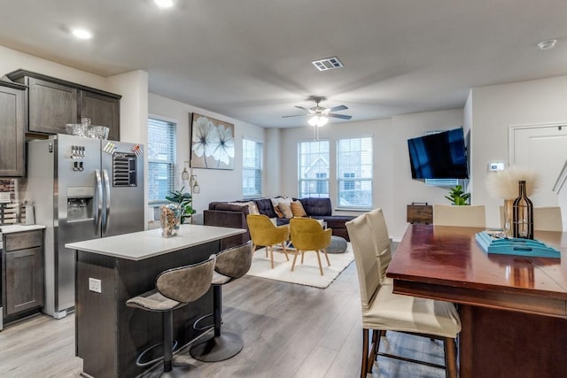 kitchen featuring stainless steel refrigerator with ice dispenser, a kitchen island, a breakfast bar area, and light wood-type flooring