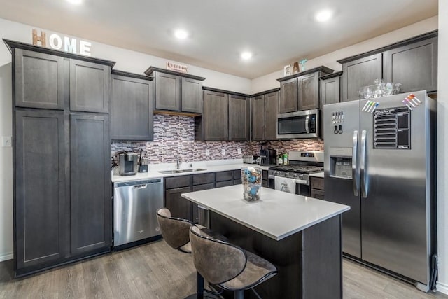 kitchen with light hardwood / wood-style floors, sink, stainless steel appliances, and a center island