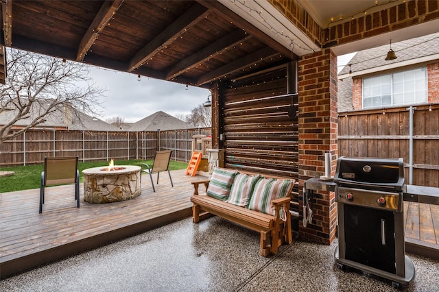 wooden terrace featuring area for grilling and a fire pit