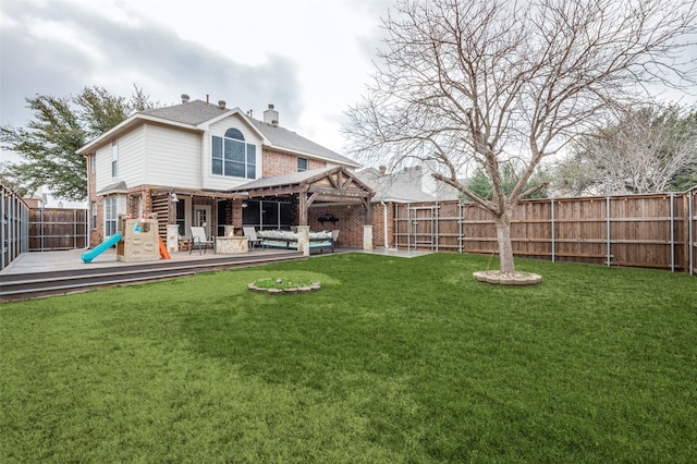 back of house featuring a yard, a patio, a playground, and a deck