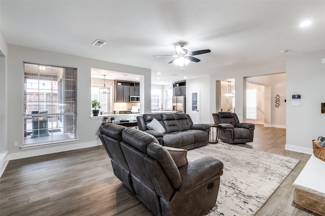 living room featuring hardwood / wood-style flooring and ceiling fan with notable chandelier