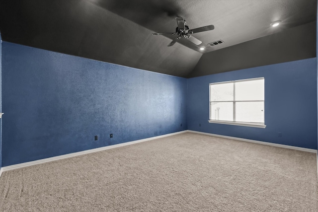 carpeted spare room featuring vaulted ceiling and ceiling fan