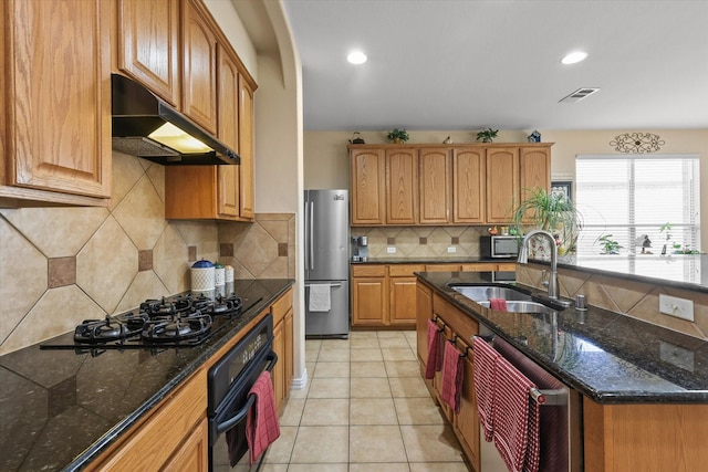 kitchen with sink, light tile patterned floors, tasteful backsplash, black appliances, and dark stone counters