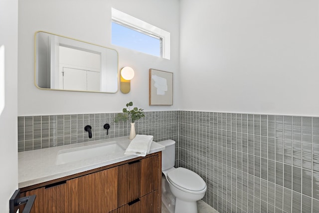 bathroom with vanity, tile walls, and toilet