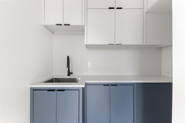 kitchen featuring tasteful backsplash, blue cabinets, and sink