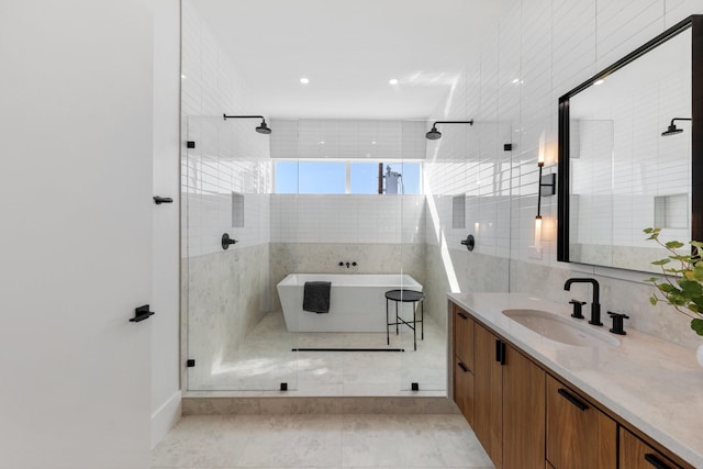 bathroom featuring vanity, tile patterned flooring, independent shower and bath, and tile walls