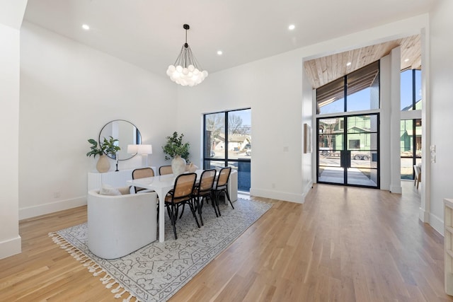 dining space with high vaulted ceiling, light hardwood / wood-style flooring, and a notable chandelier