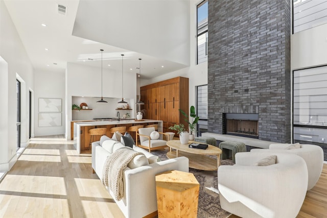 living room with a fireplace, light hardwood / wood-style floors, and a high ceiling