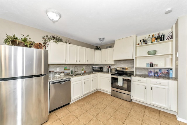 kitchen with white cabinetry, stainless steel appliances, light stone countertops, and sink