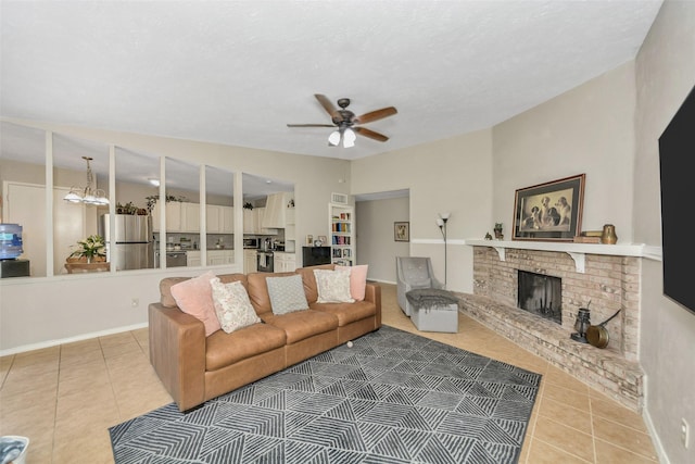 tiled living room featuring a brick fireplace and ceiling fan with notable chandelier