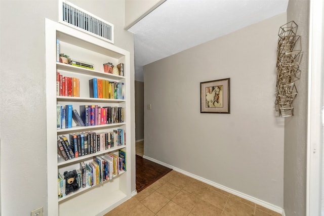 corridor featuring light tile patterned floors and built in shelves