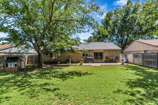 rear view of property with a storage shed, central AC, a lawn, and a patio