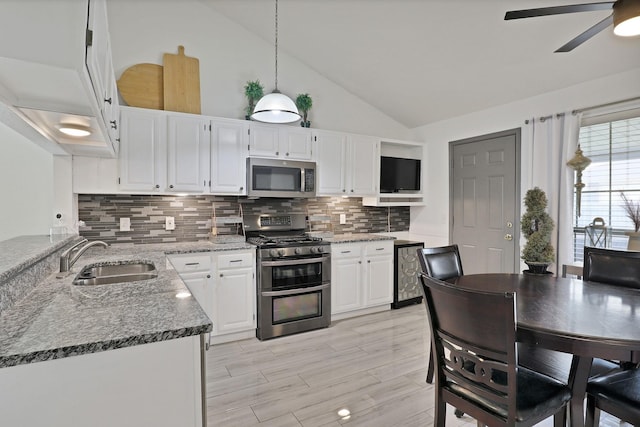 kitchen with a sink, white cabinetry, appliances with stainless steel finishes, dark stone counters, and pendant lighting