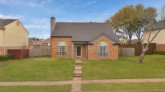 view of front of home featuring a fenced backyard, a front yard, and brick siding