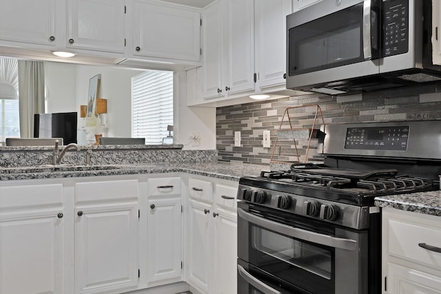 kitchen with dark stone countertops, a healthy amount of sunlight, white cabinets, and appliances with stainless steel finishes