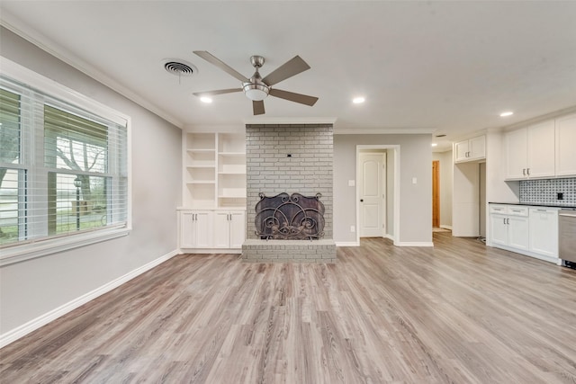 unfurnished living room featuring a fireplace, light hardwood / wood-style flooring, ornamental molding, ceiling fan, and built in shelves