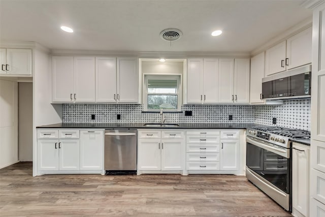728 Del Dr, Denton, TX 76207 - kitchen featuring stainless steel appliances, a sink, dark countertops, white cabinets, and recessed lighting