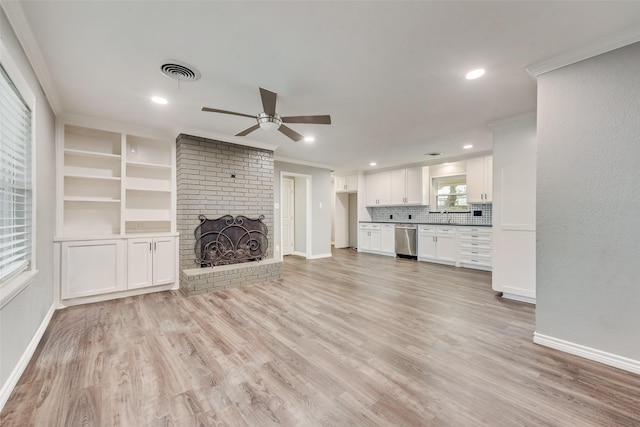 unfurnished living room featuring a brick fireplace, ornamental molding, ceiling fan, and light wood-type flooring