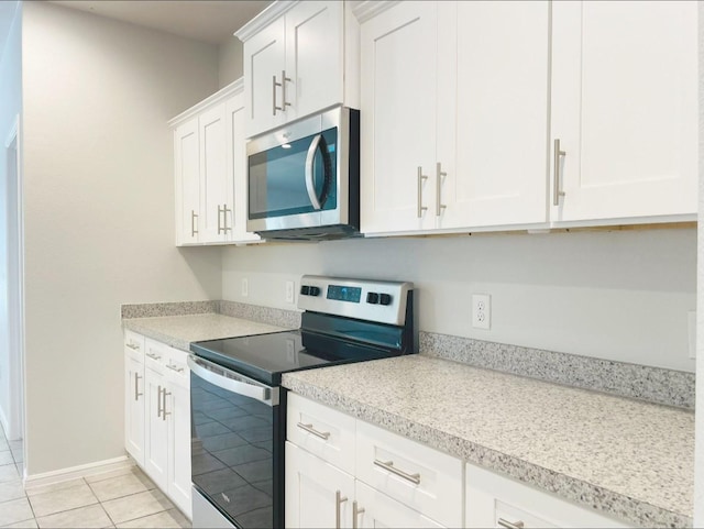 kitchen with stainless steel appliances, light tile patterned floors, and white cabinets