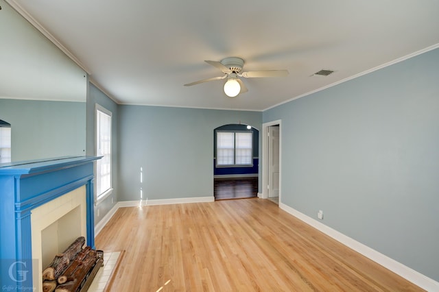 unfurnished living room with crown molding, plenty of natural light, ceiling fan, and light wood-type flooring