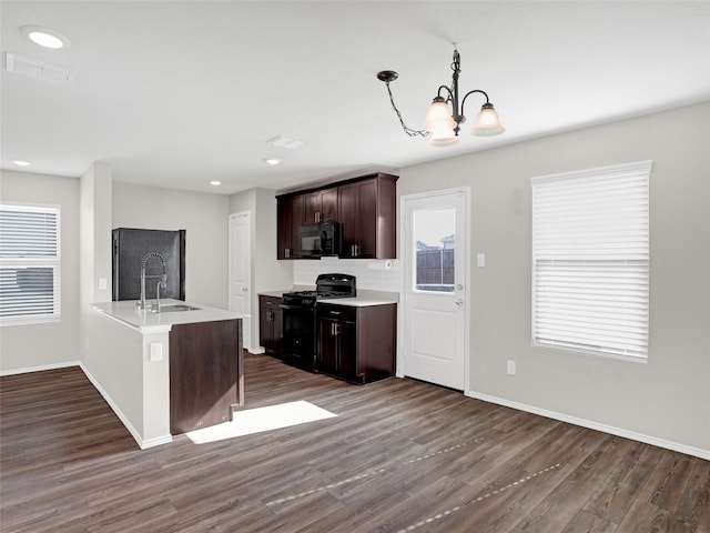 kitchen with sink, dark hardwood / wood-style floors, pendant lighting, a healthy amount of sunlight, and black appliances