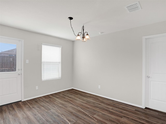 empty room featuring dark wood-type flooring and a chandelier