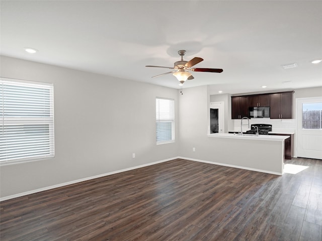 unfurnished living room with dark wood-type flooring, ceiling fan, and sink