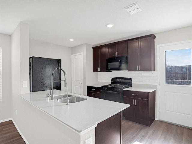 kitchen featuring sink, backsplash, light hardwood / wood-style floors, and black appliances