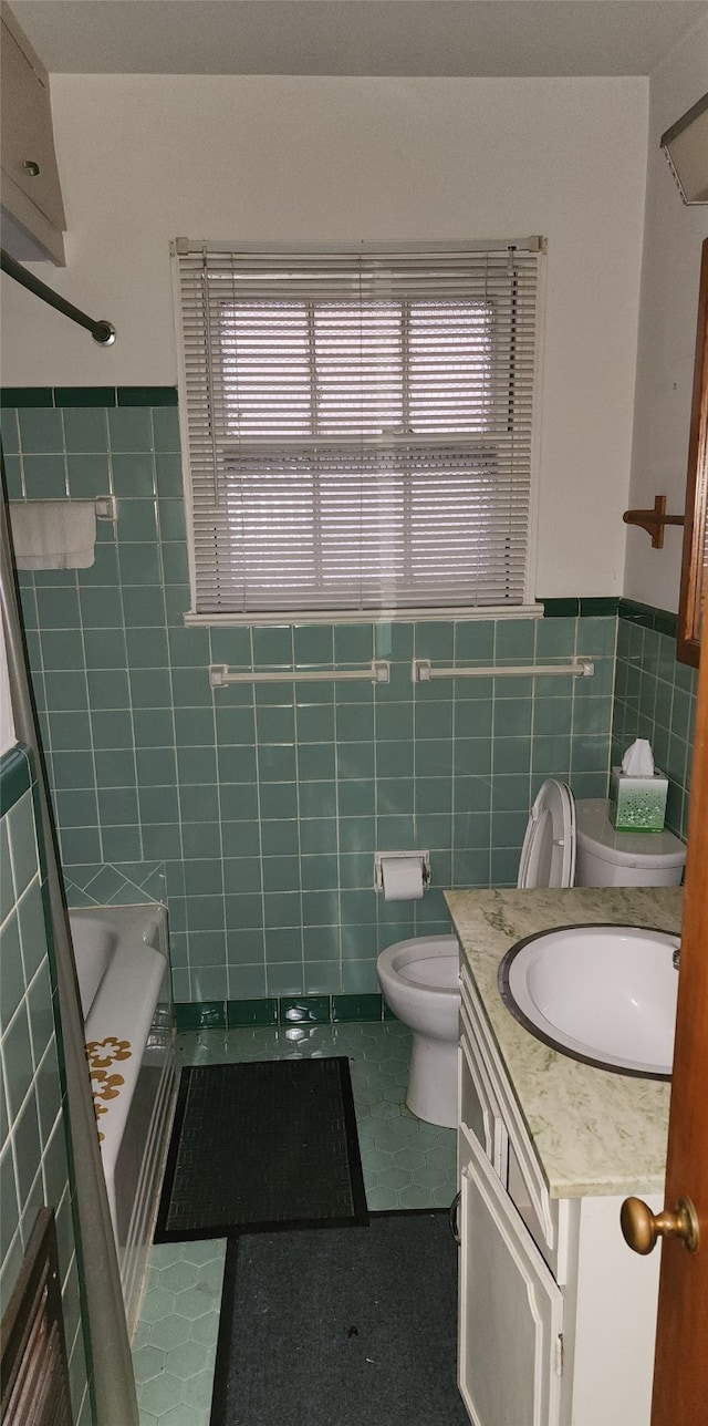 bathroom featuring tile patterned floors, vanity, toilet, and tile walls