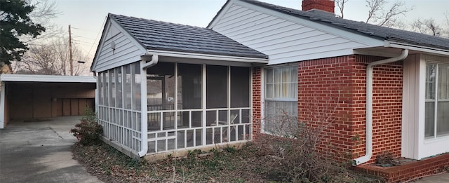 view of side of property with a sunroom and a carport