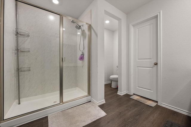 bathroom featuring wood-type flooring, a shower with shower door, and toilet