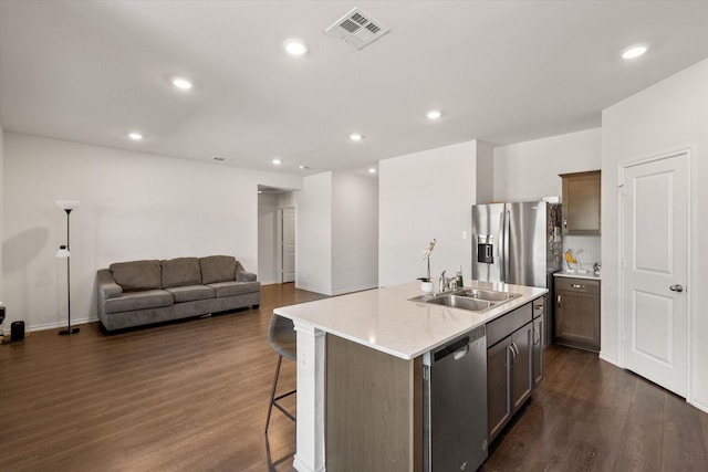 kitchen featuring sink, a center island with sink, dark hardwood / wood-style floors, and appliances with stainless steel finishes